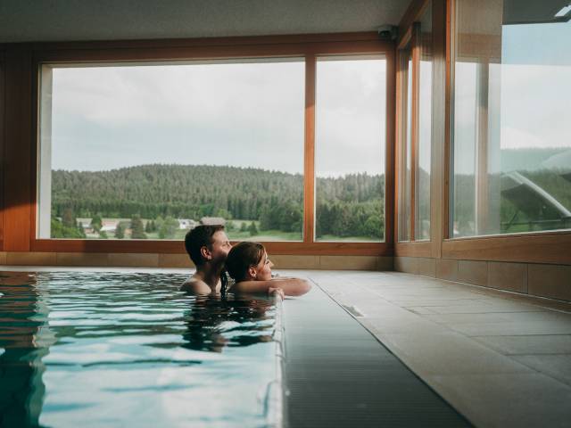 Ein Pärchen im Pool schauen aus dem Fenster des waldfrieden