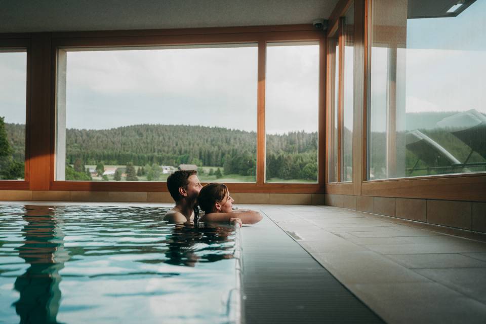 Ein Pärchen im Pool schauen aus dem Fenster des waldfrieden