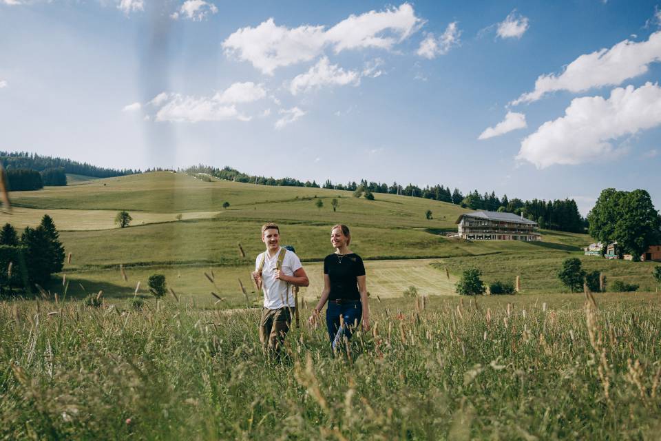 Paar beim Wandern durch die Wiese vor dem Hotel